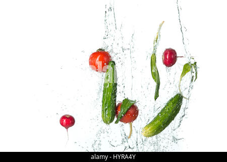 Les tomates fraîches, concombres, radis au jet d'eau sur le blanc. Banque D'Images