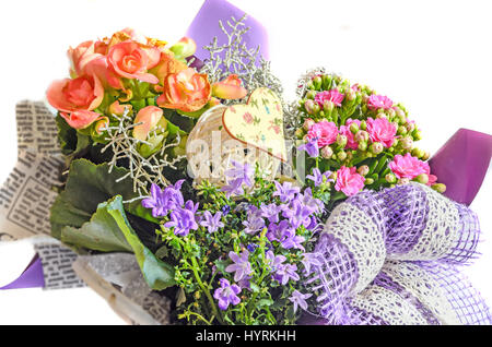 Arrangement de fleurs emballés dans du papier journal avec des fleurs rose mauve sauvage, née Calandiva fleurs, kalanchoe, violet bow. Banque D'Images