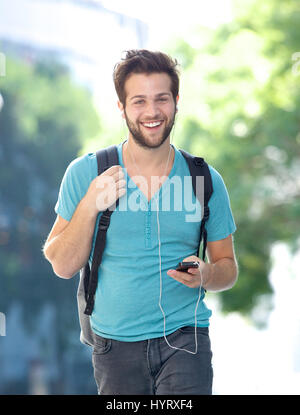 Portrait of a young man walking outdoors with cellphone Banque D'Images