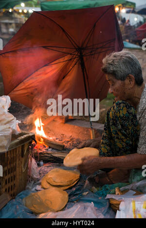 Portrait d'un vertical pauvre dame faire des crêpes de riz doux sur la rue au Cambodge. Banque D'Images