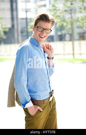 Portrait d'un jeune homme avec des lunettes smiling and holding jacket Banque D'Images