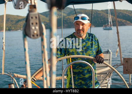 L'homme à la barre à la tête d'un yacht à voile dans la mer. Banque D'Images