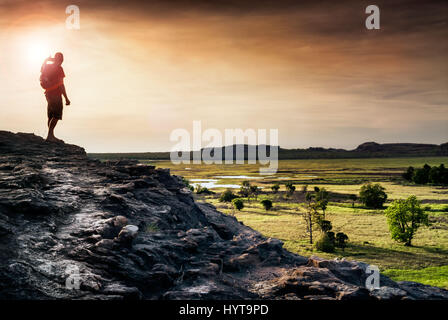 La figure solitaire regarde le coucher du soleil de Ubirr Rock regardant le Nadab d'inondation. Territoire du Nord, Australie Banque D'Images