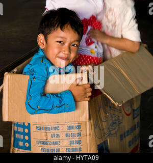 Square portrait d'un jeune garçon jouant à l'intérieur d'une boîte en carton au Cambodge. Banque D'Images