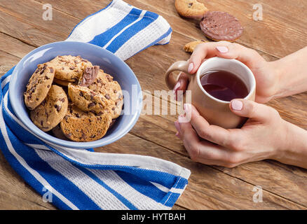 Femme mains avec thé et biscuits au chocolat sucré Banque D'Images