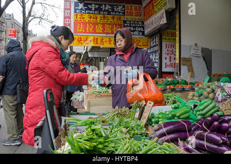 Une femme chinoise de légumes l'achat d'une position sur la rue principale dans le quartier chinois, le rinçage, Queens, New York. Banque D'Images