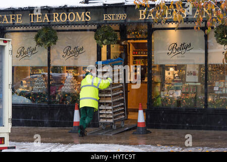 Bradford, West Yorkshire, Royaume-Uni. Neige & livraison frais est arrivé. Pains sur chariot poussé par un homme, à travers la porte du salon de thé Betty's Café. Banque D'Images