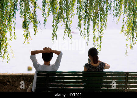 Jeune couple assis sur le banc au bord du Lac Léman embankment à Lausanne, Suisse. Banque D'Images