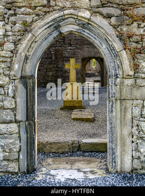 Ancien portail en pierre avec croix en arrière-plan, Corcomroe Abbey, comté de Clare, Irlande Banque D'Images