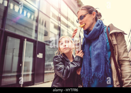 Mère et fille marchant dans les rues de la ville et eating sandwich Banque D'Images