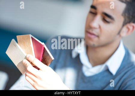 Close-up of blurred thoughtful homme noir à chandail gris holding les placages de couleurs différentes. Banque D'Images