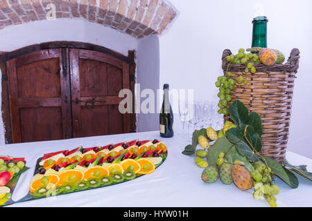 Composition de fruits et couper le verre demijohn vin couché pour l'osier. Sur une table laden avec un restaurant, avec des raisins, des figues, de figuiers de barbarie et de feuilles. Un Banque D'Images