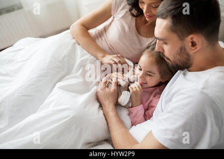 Happy child with toy et les parents au lit à la maison Banque D'Images