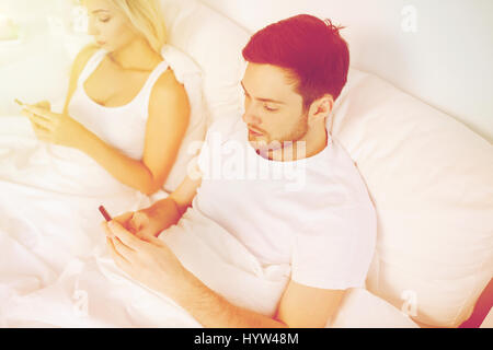 Les smartphones avec couple in bed Banque D'Images