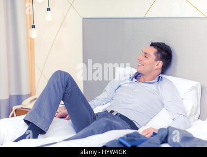 Happy businesswoman Lying in Bed in hotel room Banque D'Images