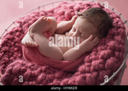 Neuf jours au nouveau-né emmailloté bébé fille et dormir dans un panier métallique doublée d'un tricot vieux rose couverture. Banque D'Images