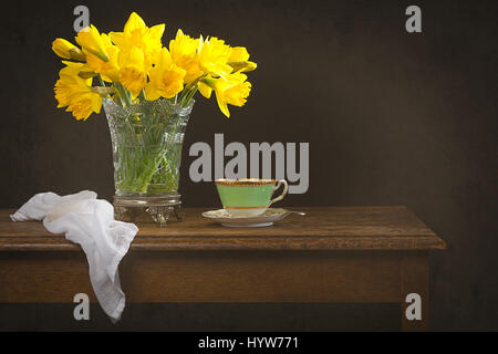 Nature morte avec un vase en verre rempli de jonquilles printemps sur table rustique Banque D'Images