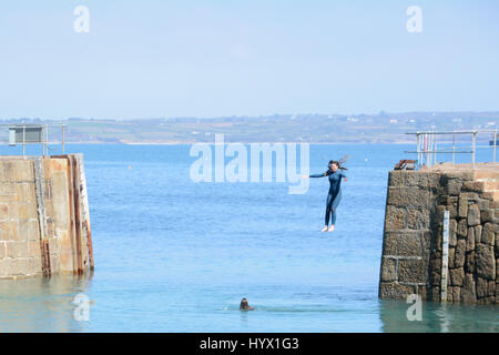 Mousehole, Cornwall, UK. 7 avril 2017. Météo britannique. Après-midi ensoleillé à Mousehole, avec les filles de sauter les murs du port dans la mer. Crédit : Simon Maycock/Alamy Live News Banque D'Images