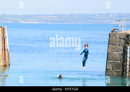 Mousehole, Cornwall, UK. 7 avril 2017. Météo britannique. Après-midi ensoleillé à Mousehole, avec les filles de sauter les murs du port dans la mer. Crédit : Simon Maycock/Alamy Live News Banque D'Images