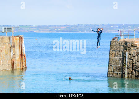 Mousehole, Cornwall, UK. 7 avril 2017. Météo britannique. Après-midi ensoleillé à Mousehole, avec les filles de sauter les murs du port dans la mer. Crédit : Simon Maycock/Alamy Live News Banque D'Images