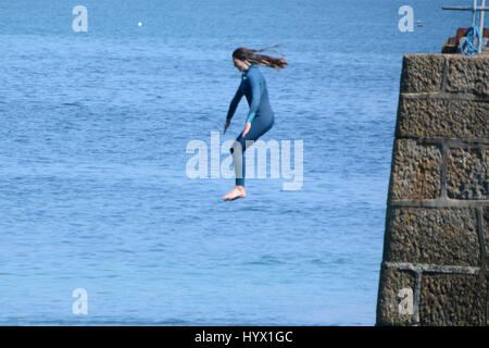 Mousehole, Cornwall, UK. 7 avril 2017. Météo britannique. Après-midi ensoleillé à Mousehole, avec les filles de sauter les murs du port dans la mer. Crédit : Simon Maycock/Alamy Live News Banque D'Images