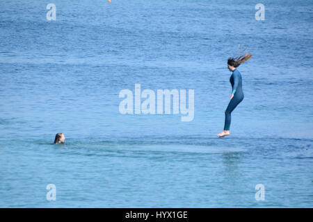 Mousehole, Cornwall, UK. 7 avril 2017. Météo britannique. Après-midi ensoleillé à Mousehole, avec les filles de sauter les murs du port dans la mer. Crédit : Simon Maycock/Alamy Live News Banque D'Images