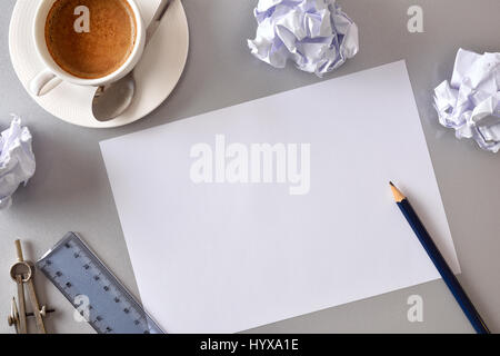 Concept recherche d'idées en affaires. Feuille blanche sur table bureau gris avec des draps froissés, café, règle et compas en arrière-plan. Vue d'en haut. Hor Banque D'Images