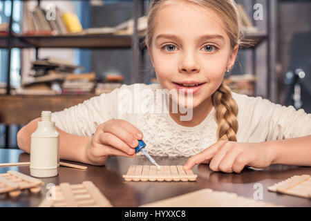 Smiling little girl la fabrication de crème glacée avec des bâtons et d'une colle Banque D'Images