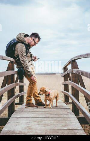 Randonneur de flatter un chien sur un pont en bois Banque D'Images