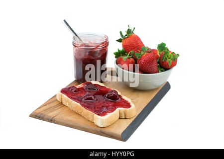 Du pain avec de la confiture de fraise sur une planche de bois. Délicieux petit-déjeuner. Fraise mûre, isolé sur fond blanc. Banque D'Images