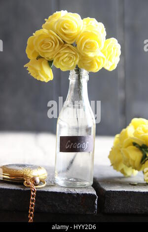 Fleurs dans une bouteille en verre et de l'étiquette avec le mot espagnol Gracias Banque D'Images