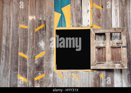 Jaune-vert-coloré en bois peint bleu bord mur et ouvrir la fenêtre de l'obturateur avec spike décoration tendance. Hameau de la tribus Khmu-Nam Ou Banque D'Images