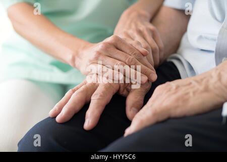 Care worker holding senior man's hands. Banque D'Images