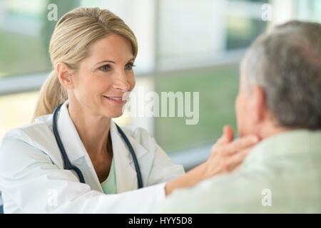 Femme médecin senior toucher le cou de l'homme. Banque D'Images