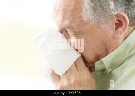 Senior man blowing nose sur les tissus. Banque D'Images