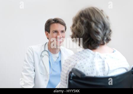 Doctor smiling at mature female patient in wheelchair. Banque D'Images