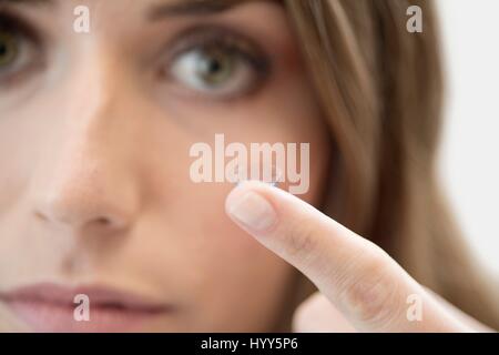 Mid adult woman avec lentille de contact sur le doigt. Banque D'Images