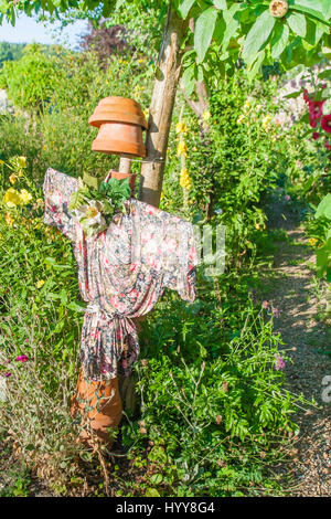 Épouvantail dans un jardin. femme épouvantail avec une robe fleurs debout dans un jardin coloré. somme, France, Europe Banque D'Images