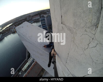 SEVASTOPOL, UKRAINE : UN Adrenaline Junkie a risqué sa vie après l'ascension d'une 195 pieds de haut monument aux héros de guerre russe WW2 juste pour obtenir une nouvelle vidéo de la ville ci-dessous. Vertigo-induisant des images et séquences vidéo montrent le grimpeur audacieux s'emmitoufler d'une échelle à l'intérieur de la spire avant de sortir sur une surface qui est incliné à 45 degrés, sans aucun équipement de sécurité. Le rooftopper promenades le long de la surface inclinée jusqu'à ce qu'il atteint le bord où il est assis et balance ses jambes tout en passant des messages sur son téléphone. C'est le vidéo a été filmé au sommet de l'Obélisque d'Bayonet-Sail Sevastopo dans Banque D'Images