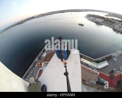 SEVASTOPOL, UKRAINE : UN Adrenaline Junkie a risqué sa vie après l'ascension d'une 195 pieds de haut monument aux héros de guerre russe WW2 juste pour obtenir une nouvelle vidéo de la ville ci-dessous. Vertigo-induisant des images et séquences vidéo montrent le grimpeur audacieux s'emmitoufler d'une échelle à l'intérieur de la spire avant de sortir sur une surface qui est incliné à 45 degrés, sans aucun équipement de sécurité. Le rooftopper promenades le long de la surface inclinée jusqu'à ce qu'il atteint le bord où il est assis et balance ses jambes tout en passant des messages sur son téléphone. C'est le vidéo a été filmé au sommet de l'Obélisque d'Bayonet-Sail Sevastopo dans Banque D'Images