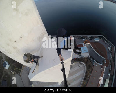 SEVASTOPOL, UKRAINE : UN Adrenaline Junkie a risqué sa vie après l'ascension d'une 195 pieds de haut monument aux héros de guerre russe WW2 juste pour obtenir une nouvelle vidéo de la ville ci-dessous. Vertigo-induisant des images et séquences vidéo montrent le grimpeur audacieux s'emmitoufler d'une échelle à l'intérieur de la spire avant de sortir sur une surface qui est incliné à 45 degrés, sans aucun équipement de sécurité. Le rooftopper promenades le long de la surface inclinée jusqu'à ce qu'il atteint le bord où il est assis et balance ses jambes tout en passant des messages sur son téléphone. C'est le vidéo a été filmé au sommet de l'Obélisque d'Bayonet-Sail Sevastopo dans Banque D'Images