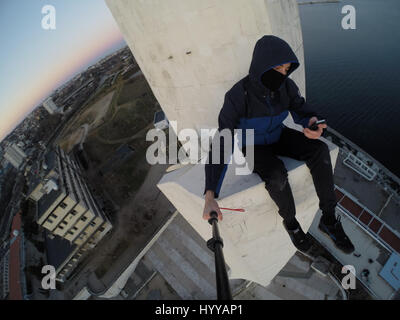 SEVASTOPOL, UKRAINE : UN Adrenaline Junkie a risqué sa vie après l'ascension d'une 195 pieds de haut monument aux héros de guerre russe WW2 juste pour obtenir une nouvelle vidéo de la ville ci-dessous. Vertigo-induisant des images et séquences vidéo montrent le grimpeur audacieux s'emmitoufler d'une échelle à l'intérieur de la spire avant de sortir sur une surface qui est incliné à 45 degrés, sans aucun équipement de sécurité. Le rooftopper promenades le long de la surface inclinée jusqu'à ce qu'il atteint le bord où il est assis et balance ses jambes tout en passant des messages sur son téléphone. C'est le vidéo a été filmé au sommet de l'Obélisque d'Bayonet-Sail Sevastopo dans Banque D'Images