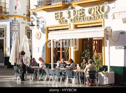 Séville, Andalousie, espagne. Clients assis au soleil à l'extérieur de l'Restaurante El 3 de oro sur la Calle Santa Maria la Blanca dans le Barrio Santa Cruz.. Banque D'Images