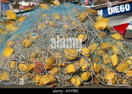 Les filets de pêche empilés sur la plage à côté d'un bateau de pêche colorés dans le petit village de pêcheurs de Curanipe dans la région du Maule au Chili. Banque D'Images