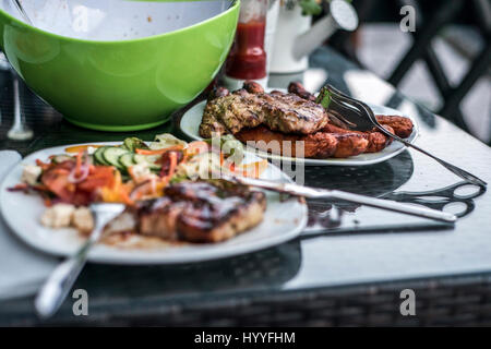 Un assortiment de délicieux de la viande grillée avec salade en arrière-plan sur plaque blanche sur la table de famille bbq party Banque D'Images