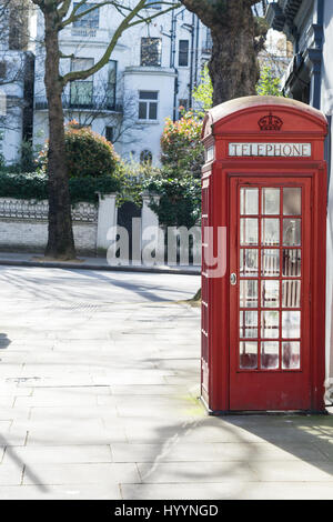 Londres - le 30 mars : cabine téléphonique rouge iconique in front of white town houses in Kensington, le 30 mars 2017. Banque D'Images