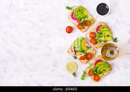 Sandwiches vegan avec avocat, radis pastèque et les tomates sur un fond blanc. Mise à plat. Vue d'en haut Banque D'Images