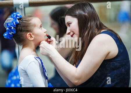 Maquillage mère gagne sa fille. Mother putting lipstick sur sa fille sur fond de miroir. Aider maman petite fille d'utiliser le rouge à lèvres avant d'un Banque D'Images