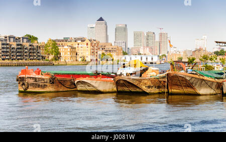 L'horizon de quartier des Docklands de Londres s'élève au-dessus de vieux waterhouses industrielle et de barges sur la tamise à bermondsey. Banque D'Images