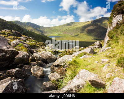 Un petit ruisseau de montagne rocheuse tombe de Pedlar's Lake vers l'Owenmore vallée, avec Brandon Mountain derrière, près de l'Conor Pass à travers le mo Banque D'Images